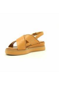 Sandalo in pelle color cuoio con design a fascia incrociata, punta aperta e cinturino alla caviglia regolabile. Presenta una soletta imbottita e una suola a zeppa bassa.