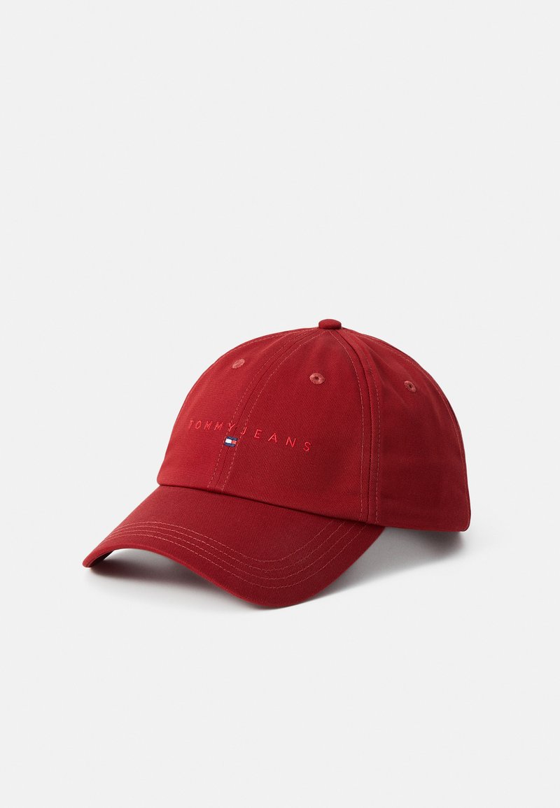 Red cotton baseball cap with embroidered "TOMMY JEANS" logo. Features a curved brim, adjustable back strap, and ventilation eyelets.