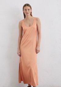 Różowa satynowa sukienka maxi z dekoltem w serek i bocznym rozcięciem. Gładka faktura i dopasowany krój podkreślają jej elegancki design.