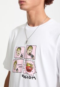 Hvid bomulds t-shirt med et comic-stil grafisk design bestående af fire paneler. Tegneseriefigurer med forskellige ansigtsudtryk, "Volcom" trykt nedenfor.