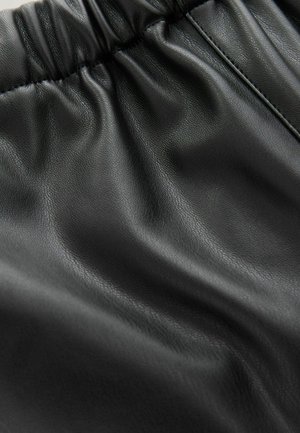 Mustast faux nahkakangast, millel on kogutud elastne vöökoht ja tekstuuriga pind.