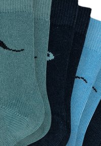 Tre par ribbede sokker i forskellige nuancer: teal, mørk navy og lyseblå, hver med et lille, enkelt sort mønster på siden.