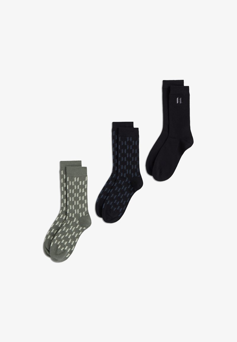 Trois paires de chaussettes mi-mollet avec motif vert olive et blanc, motif bleu marine et noir, et noir uni avec un petit logo près du haut.