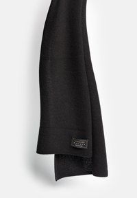 Czarny kaszmirowy szal o miękkiej teksturze, w kształcie prostokąta, z małą metką informującą "100% kaszmir, wyprodukowano w Polsce".