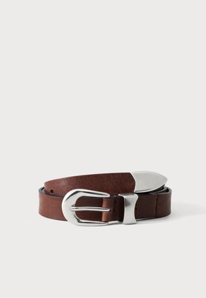 Ceinture en cuir marron enroulée avec une boucle incurvée argentée et une pointe argentée, photographiée sur un fond blanc.