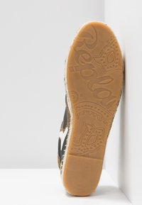 Semelle d'une chaussure décontractée avec une semelle extérieure en caoutchouc à motif comportant le mot "Replay" et des motifs décoratifs en couleur marron clair.