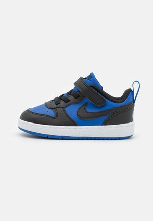 Basket Nike enfant bleu et noir avec semelle blanche, lacets noirs et une bride velcro noire sur fond blanc.