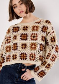 Crochet-style top with a grid pattern in shades of maroon, rust, and beige. Features long sleeves and a cropped design, textured finish.