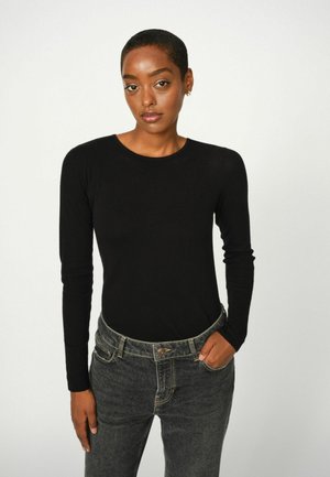 Zwarte long-sleeve top gemaakt van zachte stof, gecombineerd met donkere jeans met een riem en een knoopdetail. Effen kleur, aansluitend ontwerp.