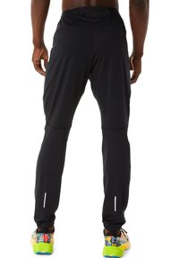 Pantalons de sport noirs en tissu flexible, avec un design fuselé, une taille élastique et des accents réfléchissants.