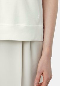 Light beige sweatshirt with ribbed hem and cuffs. Smooth cotton fabric and minimalistic design. Logo detail visible on the left side.
