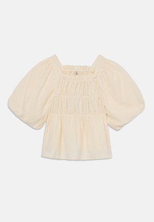 Lys beige bluse med puffermer, smockede detaljer og firkantet halsutskjæring. Laget av lett, teksturert stoff.