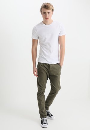 Weißes Kurzarm-T-Shirt kombiniert mit olivgrünen Hosen und schwarzen Sneakern. Einfaches Design mit einer taillierten Silhouette und lässigem Charme.