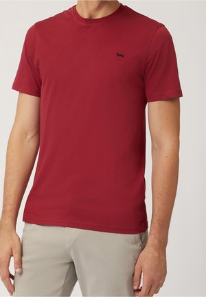Czerwona bawełniana koszulka z okrągłym dekoltem i krótkimi rękawami, z małym granatowym logo na piersi. Gładka tekstura, prosty design.