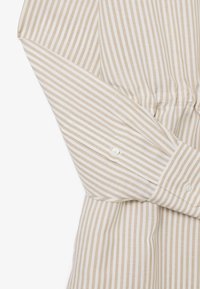 Beiges und weißes Hemd mit langen Ärmeln, vertikal gestreift, mit geknöpften Manschetten und einem dezenten Detail mit Raffungen an der Taille.