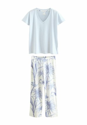 Hellblaues V-Ausschnitt-T-Shirt aus weichem Material, kombiniert mit cremefarbenen Hosen, die mit einem blauen botanischen Druck von Bäumen und Vögeln versehen sind.