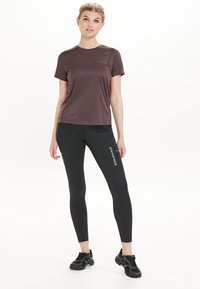 Dieprode vochtregulerende t-shirt gecombineerd met zwarte slim-fit leggings met de tekst "ENDURANCE". Beide gemaakt van rekbare, lichte materialen.