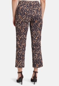Pantaloni cropped aderenti di colore blu navy con un motivo geometrico marrone e crema; realizzati in tessuto liscio; abbinati a scarpe con tacco alto marroni scuri.