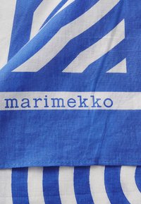 Blå og hvidt stof med markante, geometriske mønstre med skiftende striber og former. "marimekko" trykt med en enkel blå skrifttype på hvid.