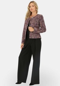 Teksturowana purpurowo-różowa kurtka z tweedu z okrągłym dekoltem i zapięciem na guziki, w połączeniu z luźnymi czarnymi spodniami. Gładki materiał, dopasowany krój.