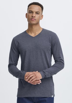 Camiseta gris de manga larga con escote en V, hecha de una tela suave; presenta un diseño ajustado con una textura suave y detalles de costura minimalista.