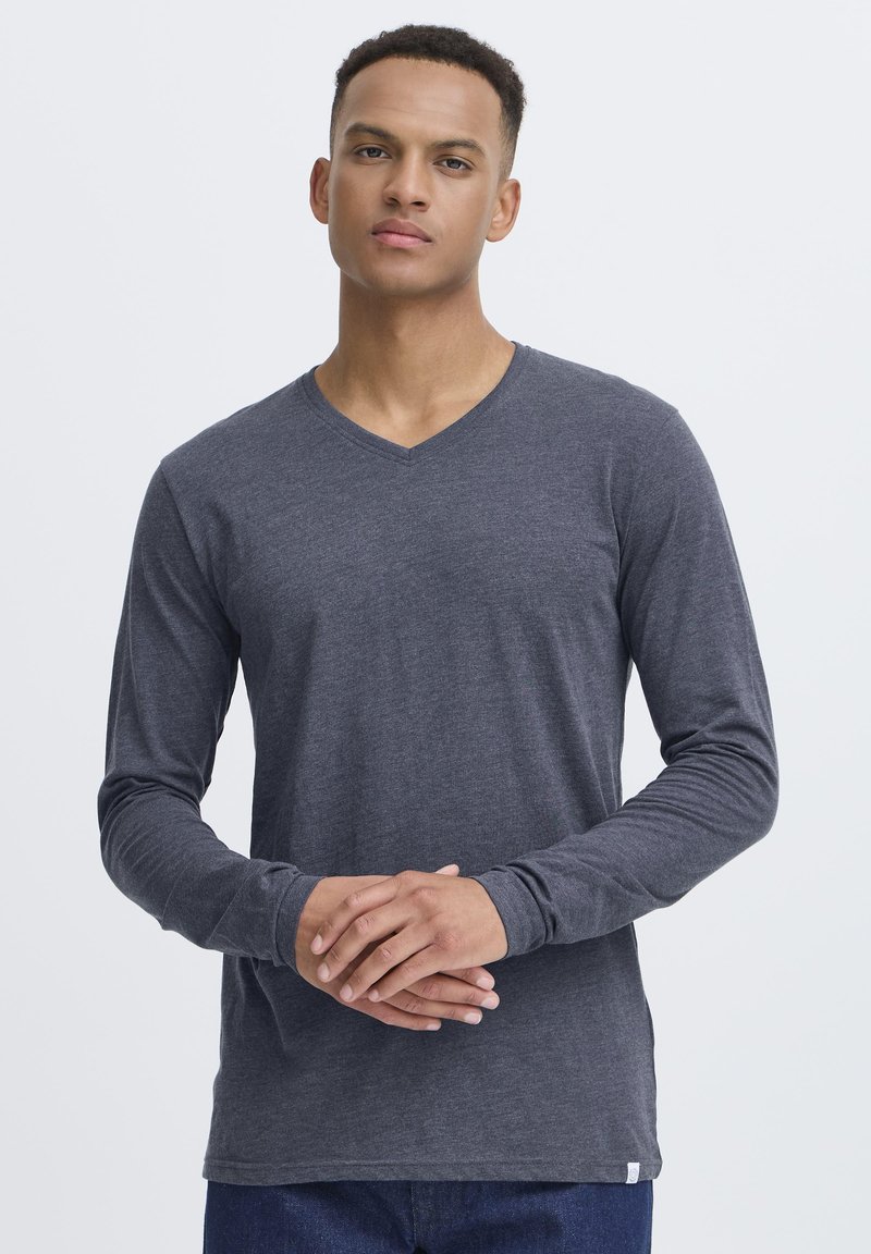 Langærmet grå V-hals T-shirt lavet af blødt stof; har en tætsiddende design med en glat tekstur og minimalistiske syninger.