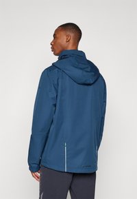 Jūras spēku ūdensizturīga jaka ar kapuci, elastīgām aprocēm, izliektu apakšmalu, atstarojošiem elementiem un logotipu aizmugurē. Elpojošs audums.