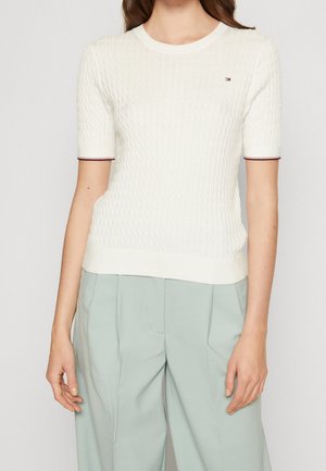 Hvid strikket kortærmet sweater med et struktureret mønster, der har kontrasterende maroon striber ved ærmerne og halsudskæringen.