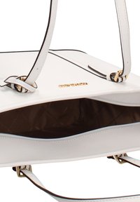 Witte handtas met gouden hardware, voorzien van een gestructureerde afwerking, een interieur van bruin stof en dubbele draagriemen. Open bovenkant ontwerp.
