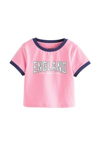 Vaaleanpunainen lyhythihainen crop-top, jossa on tummansininen reunus ja "ENGLAND Brave Strong Fierce" painettuna paksuilla kirjaimilla rinnan kohdalla.