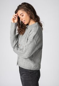 Gray cardigan with a crew neckline, button closure, and ribbed cuffs. Soft texture and loose fit with dropped shoulders.