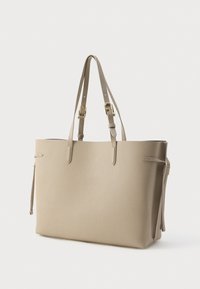 Geantă tote bej din piele, cu două curele lungi, suprafață texturată, deschidere superioară și ciucuri laterali. Accente din metal auriu.