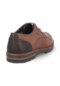 Zapato de cuero marrón con un tacón de un marrón oscuro en contraste, superficie texturizada, puntera redonda y una suela de rayas multicolor. Presenta cordones y un detalle de logo.