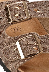 Sandalias de taupe brillantes con dos hebillas metálicas ajustables, tejido texturizado y plantillas de ante marrón. Presentan acentos en forma de diamante.