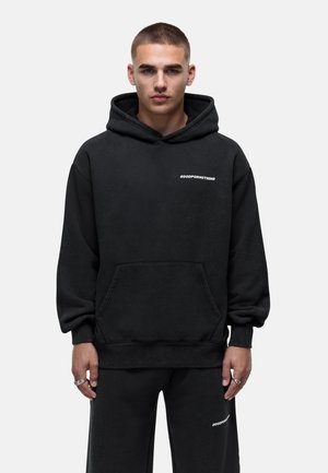 Black fleece hoodie with a kangaroo pocket, ribbed cuffs, and "GOODFORNOTHING" logo in white. Cohesively styled with matching black joggers.