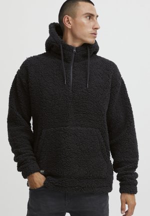 Black fleece hoodie with a textured, fluffy surface. Features a half-zip front, a large kangaroo pocket, and adjustable drawstring hood.