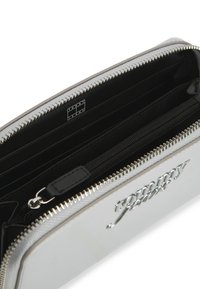 Ασημένιο πορτοφόλι με γυαλιστερή επιφάνεια και ανάγλυφο λογότυπο. Διαθέτει κλείσιμο με φερμουάρ, πολλαπλές θήκες για κάρτες και εσωτερικό διαμέρισμα για κέρματα με φερμουάρ.