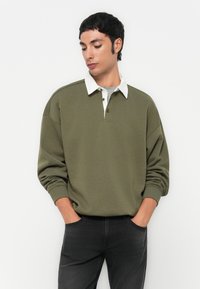 Olivgrüner Sweatshirt mit weißem Kragen, langen Ärmeln und entspannter Passform. Verfügt über eine Knopfleiste mit zwei Knöpfen und gerippten Bündchen.