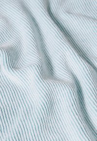 Ljusblått tyg med en mjuk, texturerad yta och fina vertikala ränder, varsamt draperat för att visa sin släta, vävda kvalitet.