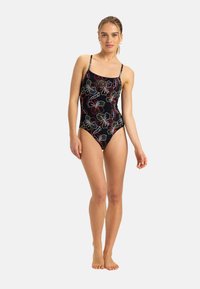Zwarte ééndelige badpak met kleurrijke florale patronen, dunne verstelbare bandjes en een klein "Roxy" logo op de borst. Gladde stoftextuur.