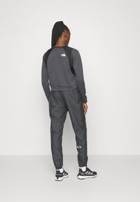 Tmavě šedá mikina s texturovaným povrchem a černými doplňky, doplněná černými lehkými tepláky s bílým logem na stehně.