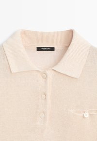 Polo beige en tricot avec col côtelé, trois boutons sur le devant, petit détail de poche boutonnée et étiquette Massimo Dutti à l'intérieur du col.