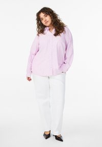 Roze-wit gestreept overhemd met knopen en lange mouwen, gecombineerd met een witte broek en zwarte pumps met puntige neus. Gladde stoftextuur.