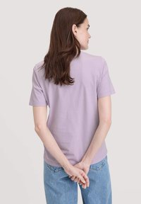 Lichtpaarse t-shirt met korte mouwen, ronde halslijn, gemaakt van katoen. Informele pasvorm met een gladde textuur, gecombineerd met blauwe denim jeans.