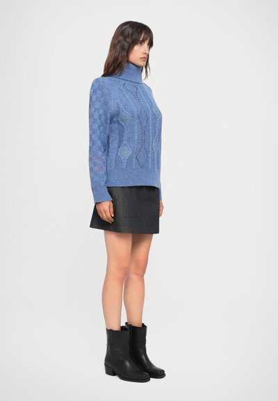 Maglione a collo alto blu a lavorazione a maglia con motivi geometrici, abbinato a una gonna di jeans nera e stivaletti neri. Tessuto morbido, design casual.