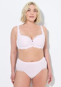 Lichtroze lingerieset met een kanten beha met een decoratieve zwarte knoop en bijpassende hoogsluitende slip met kanten afwerking.