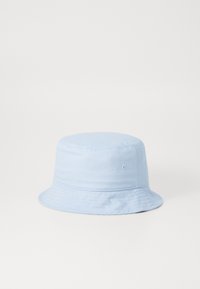 Lys blå bøttehatt laget av stoff, med en rund krone og bred, nedover skrånende skygge, med sømdetaljer og ventilasjonshull.