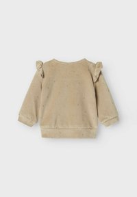 Lichte beige velours sweater met schouderruffles, ronde hals, lange mouwen en een klein stippenpatroon over de gehele stof. Zacht materiaal.