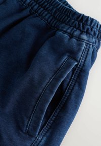 Dunkelblaue Sweatpants mit einem gerippten elastischen Bund, ausgestattet mit einer Seitentasche und glattem Stoff.
