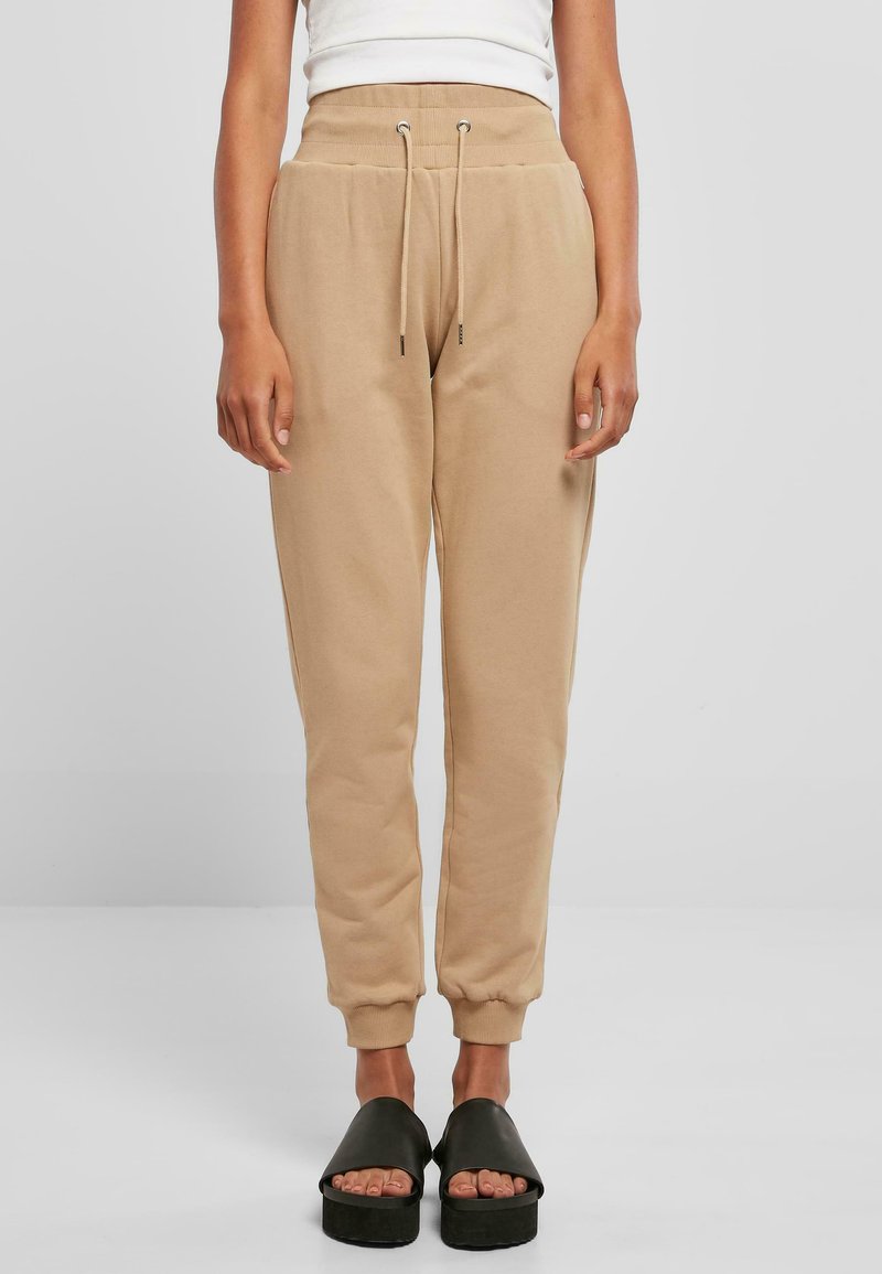 Beige joggebukser laget av mykt stoff, med elastisk midje med snøring, ribbestrikkede mansjetter og avslappet passform.